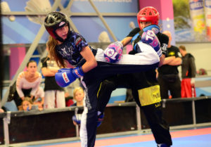 Female cadets and teens show advanced kicking techniques in continuous light contact competition.