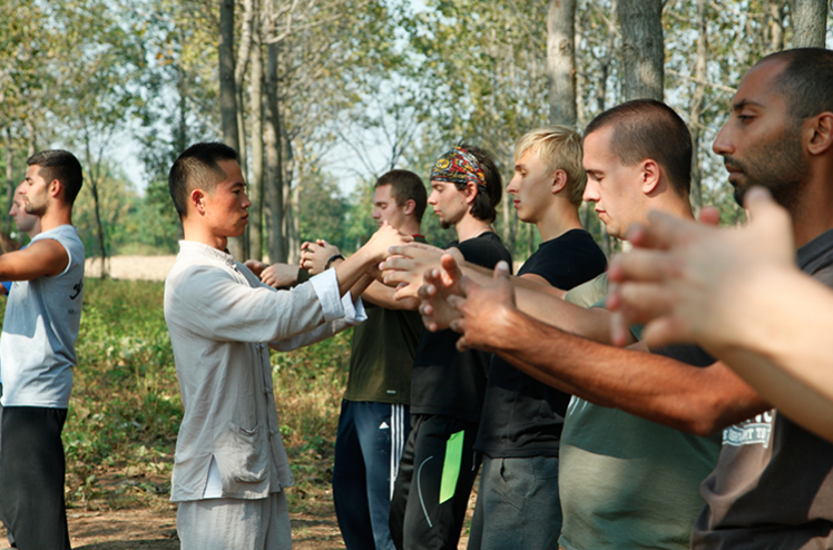 Bao Shifu making adjustments while students do qigong. 